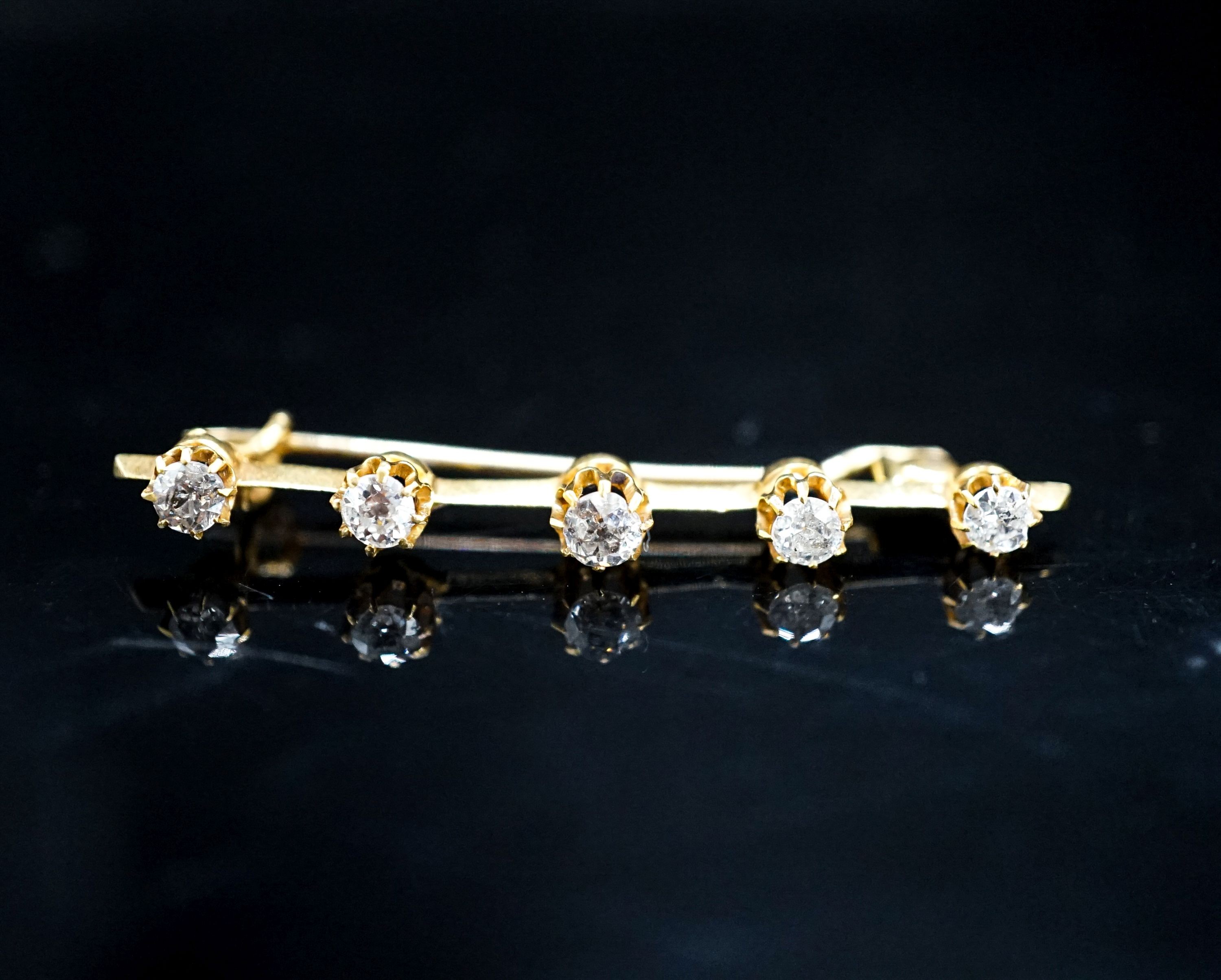 A yellow metal and five stone diamond set bar brooch, 45mm, gross weight 2.8 grams.